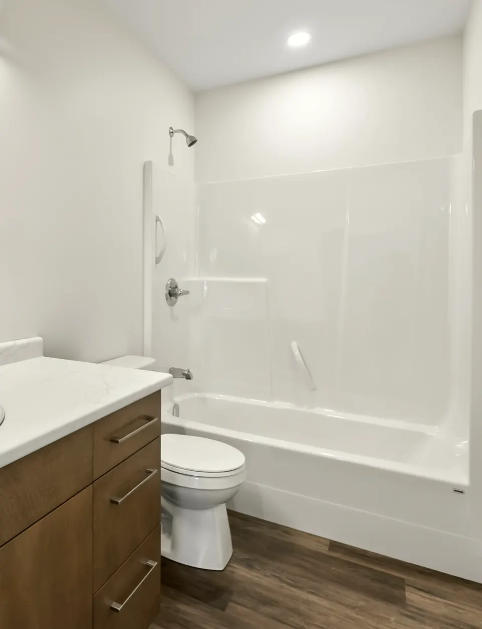 Bathroom with a tub surround and a wood-tone vanity with a white counter