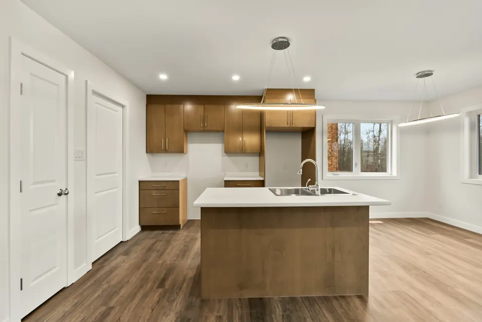 Open kitchen with a maple-tone island, pendant lights and vinyl plank flooring